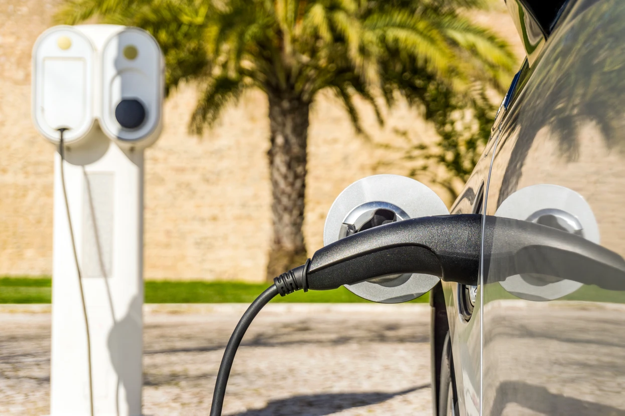 Scène extérieure ensoleillée avec véhicule électrique en cours de recharge