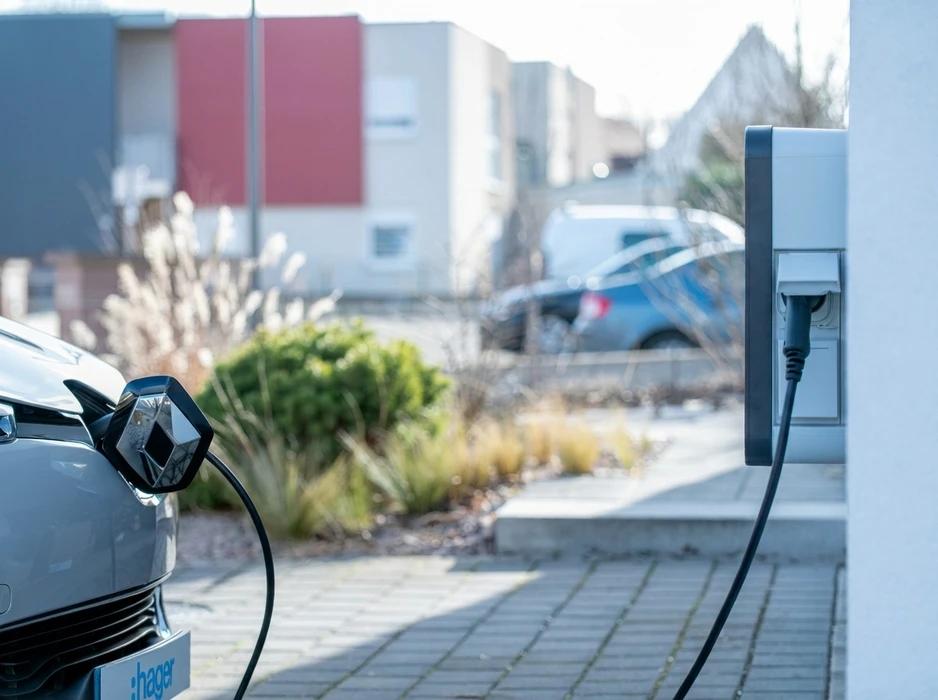 Véhicule électrique Renault branché sur une borne de recharge murale (wallbox) installée en façade d'immeuble résidentiel