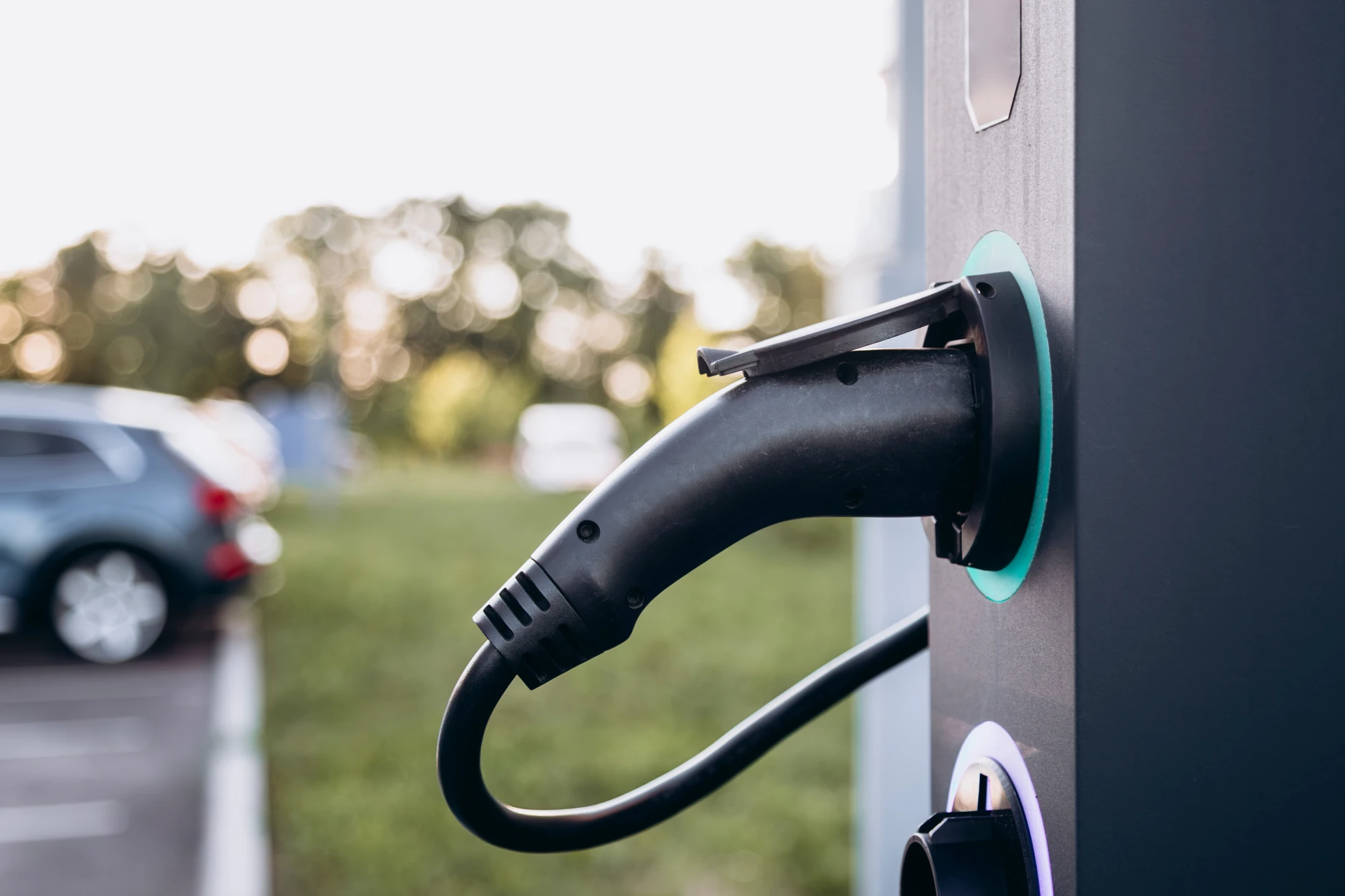 Électricien en combinaison bleue travaillant dans local technique, manipulant pince ampèremétrique rouge près tableau électrique