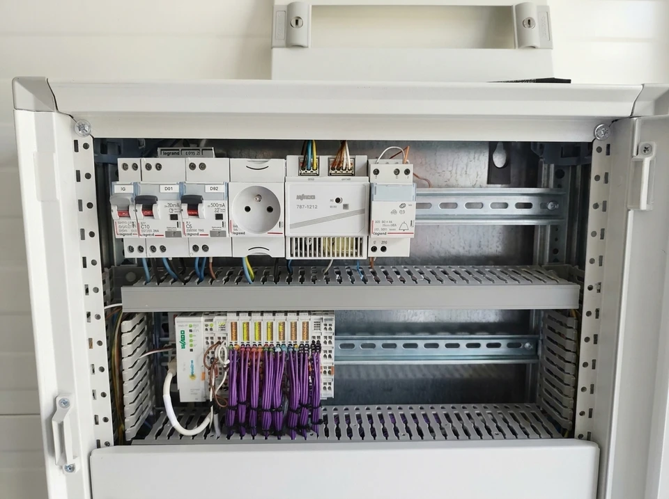 Un technicien intervient sur un tableau électrique domestique ouvert, utilisant un tournevis à manche isolé pour ajuster les disjoncteurs modulaires
