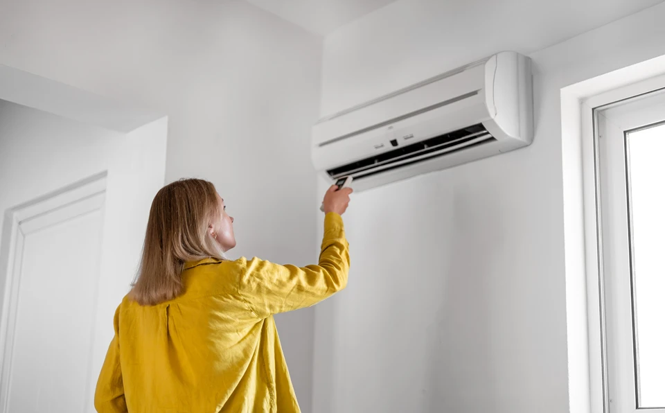 Technicien en climatisation effectuant la maintenance d'une unité de climatisation murale dans un intérieur moderne