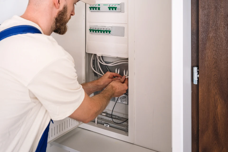 Plans techniques électroniques déroulés sur une surface de travail avec multimètre numérique noir et cordons de mesure rouge et noir