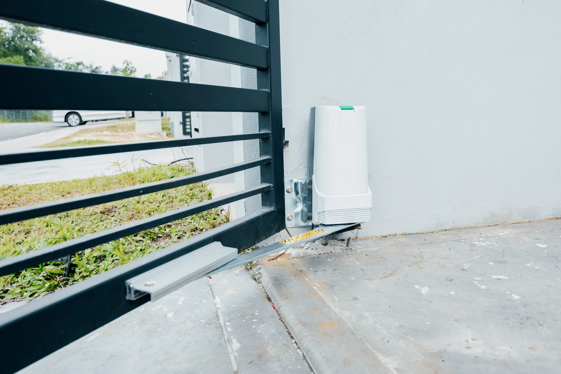 Portail automatique résidentiel en bois avec piliers maçonnés, installé devant une maison moderne