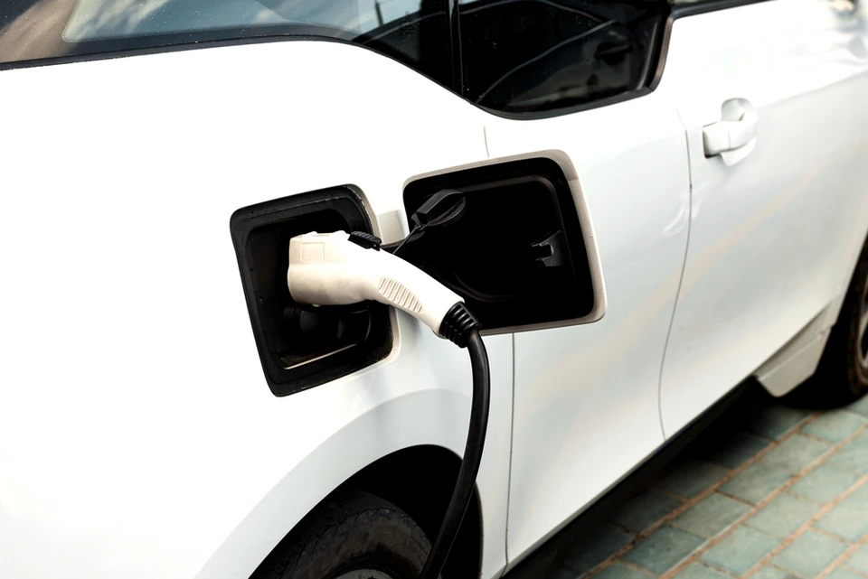 Scène extérieure urbaine avec véhicule électrique BMW i3 argenté en charge via borne de recharge publique